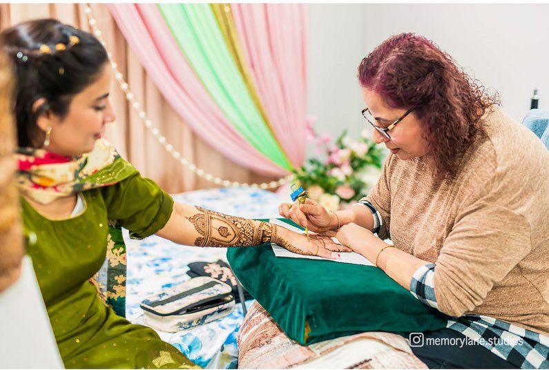 Henna being applied to a guest's hand at a mehndi event