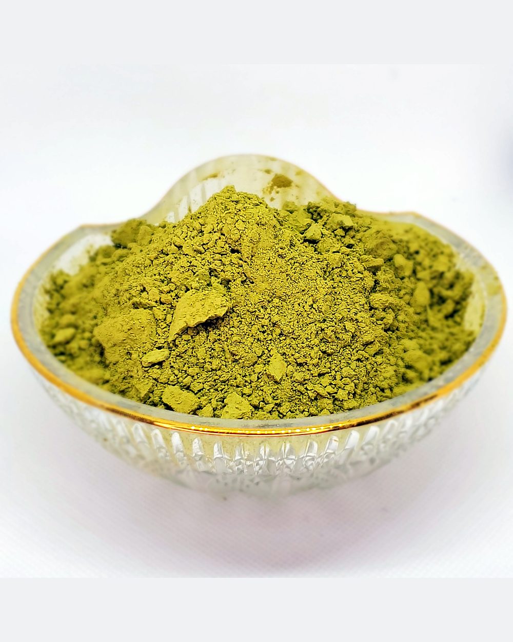 A glass bowl of loose green henna powder