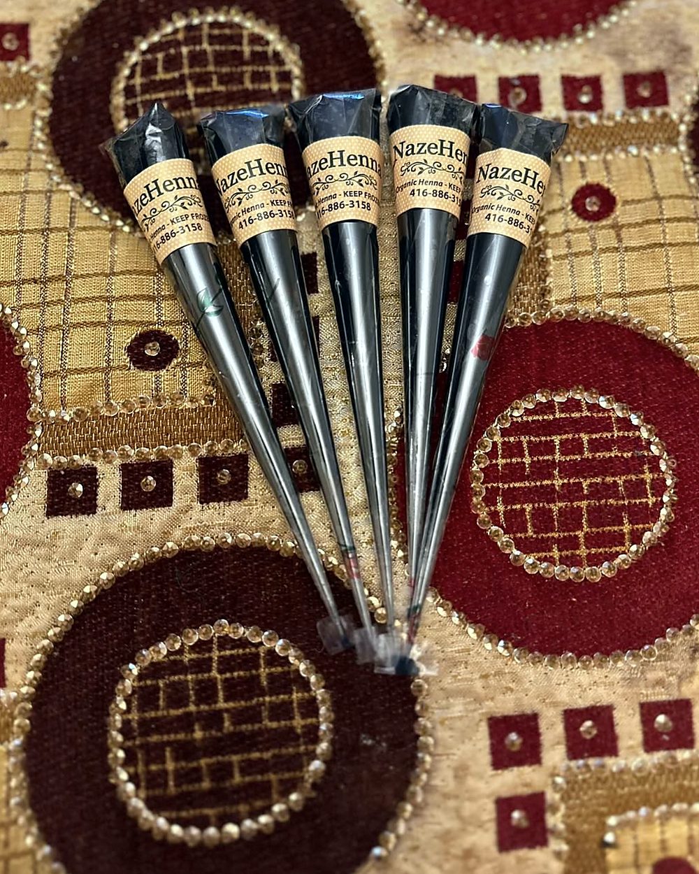 Five dark Naz-e-Henna jagua cones on a patterned cloth