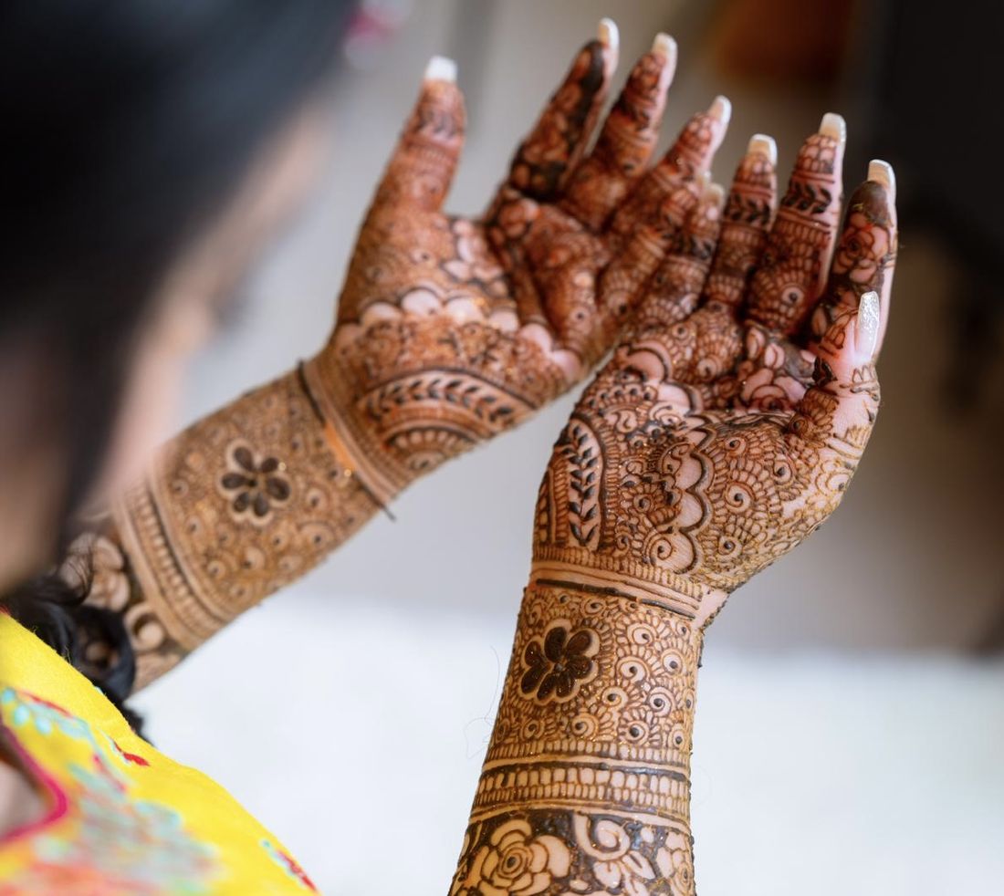 Close-up of detailed bridal henna on raised hands